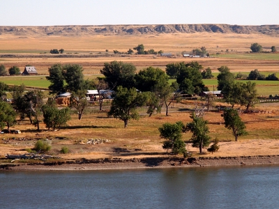 [Blue river with several feet of bank visible. Most of ground vegetation is wheat colored.]